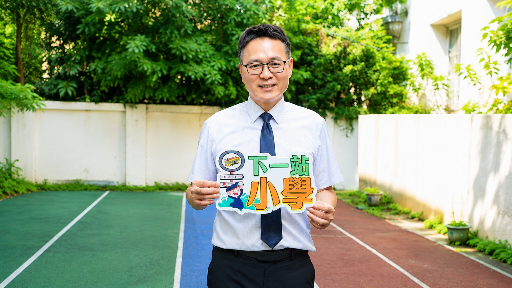 彭康助校長於校園跑道上手持「下一站小學」看板微笑合影。